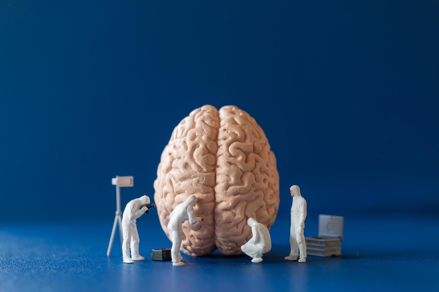 personas en miniatura, científicos que observan y discuten el cerebro humano, la atención médica y el concepto de servicio médico quirúrgico. foto