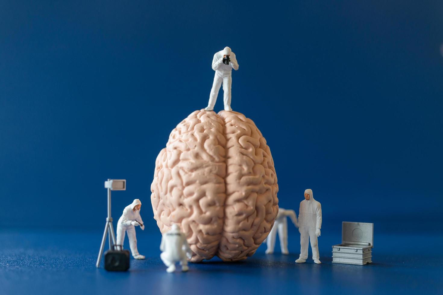 personas en miniatura, científicos que observan y discuten el cerebro humano, la atención médica y el concepto de servicio médico quirúrgico. foto