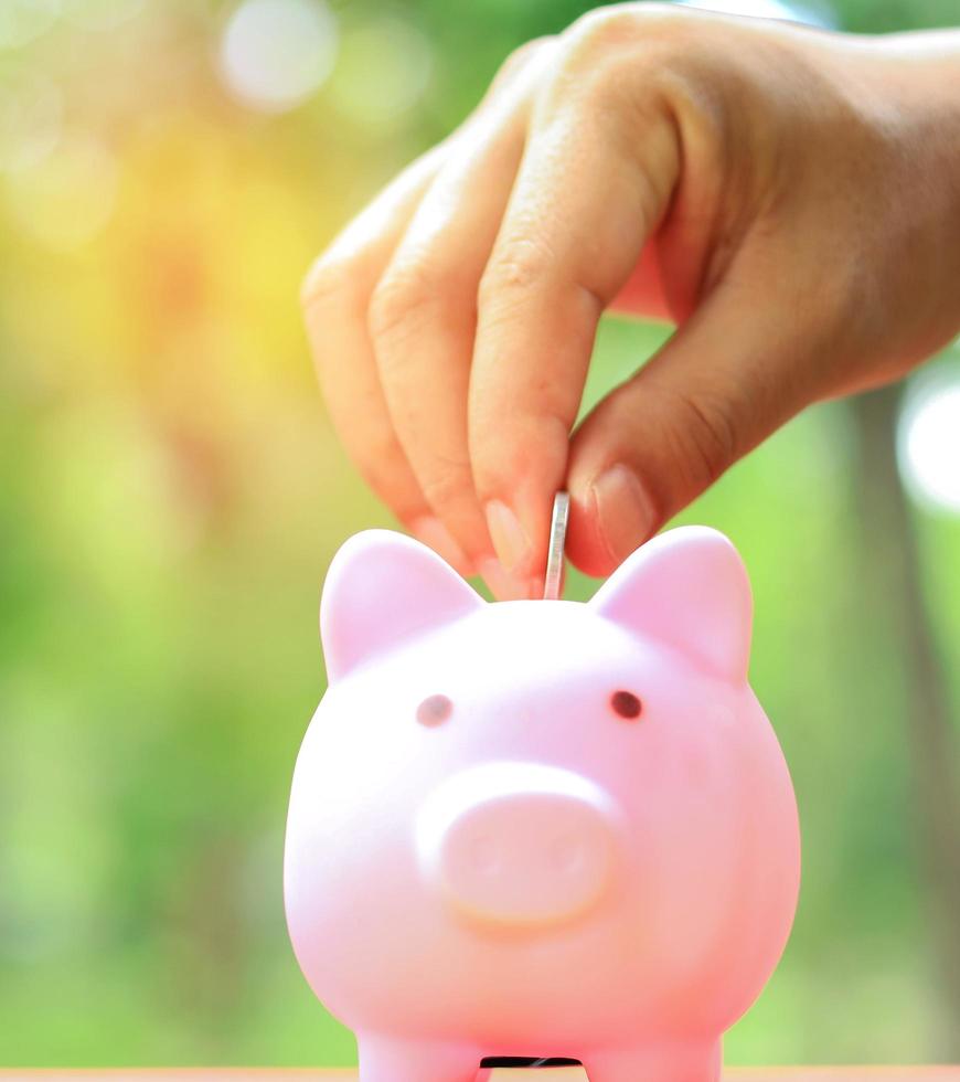 Hand putting piggy bank and coin with natural blurred background, concept money-saving for buying a car photo