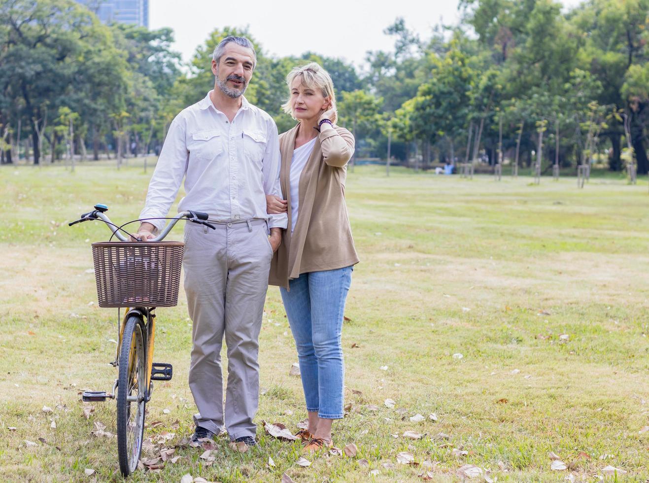 Ancianos caucásicos pasean felizmente en el parque con una bicicleta foto