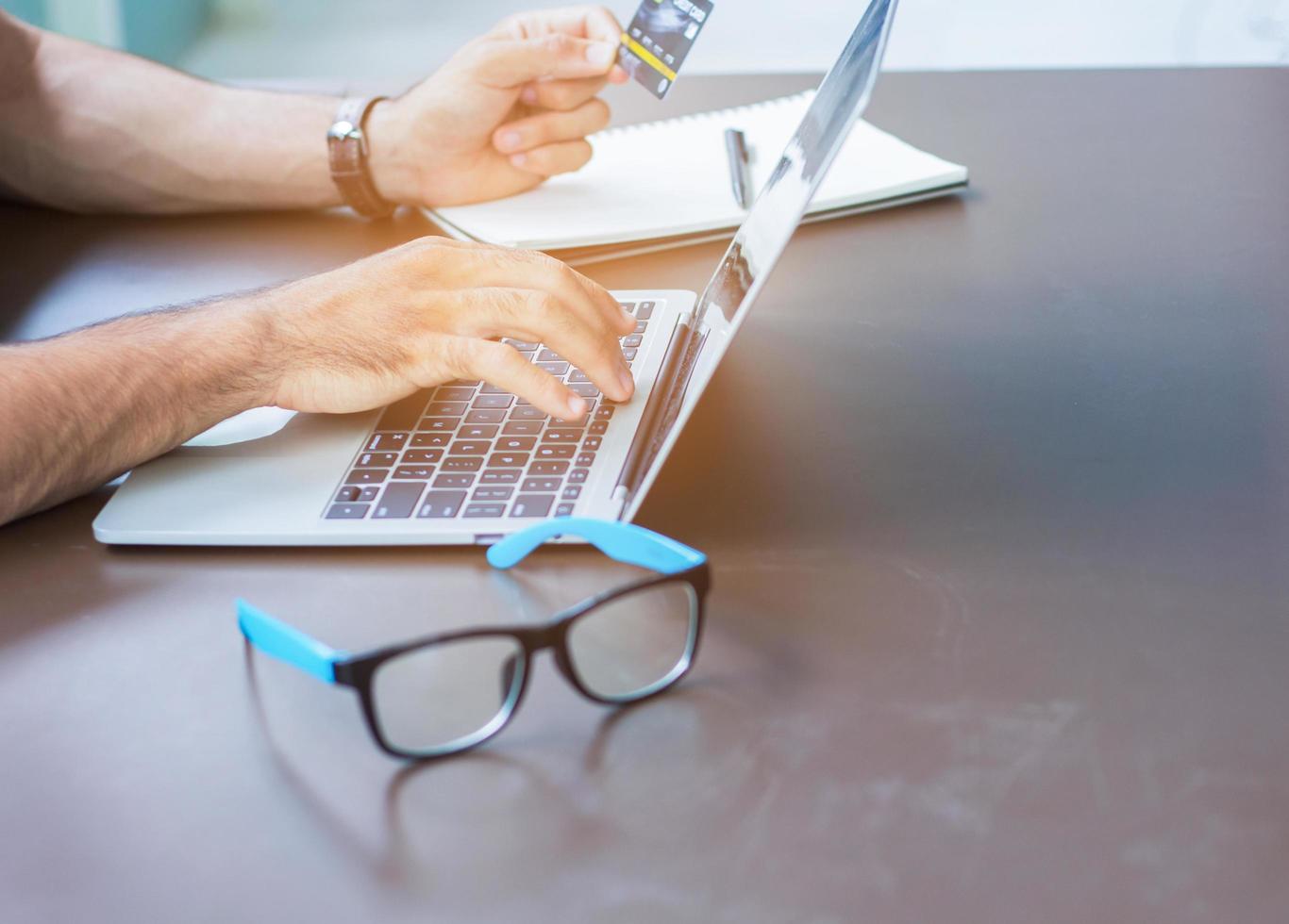 Close-up of hand working with a laptop at home and holding a credit card photo