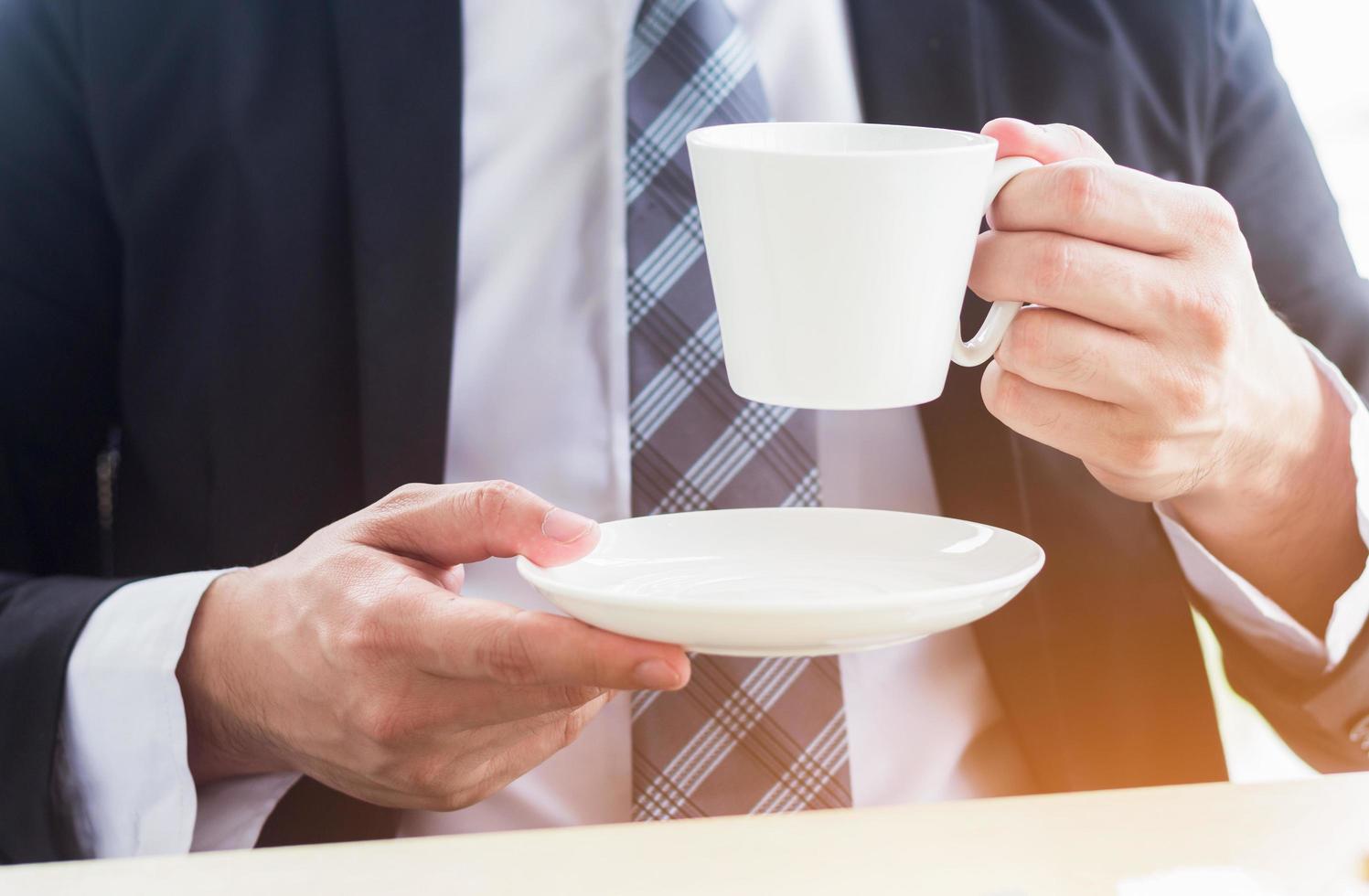 de cerca, joven hombre de negocios sosteniendo una taza de café con leche en la oficina foto