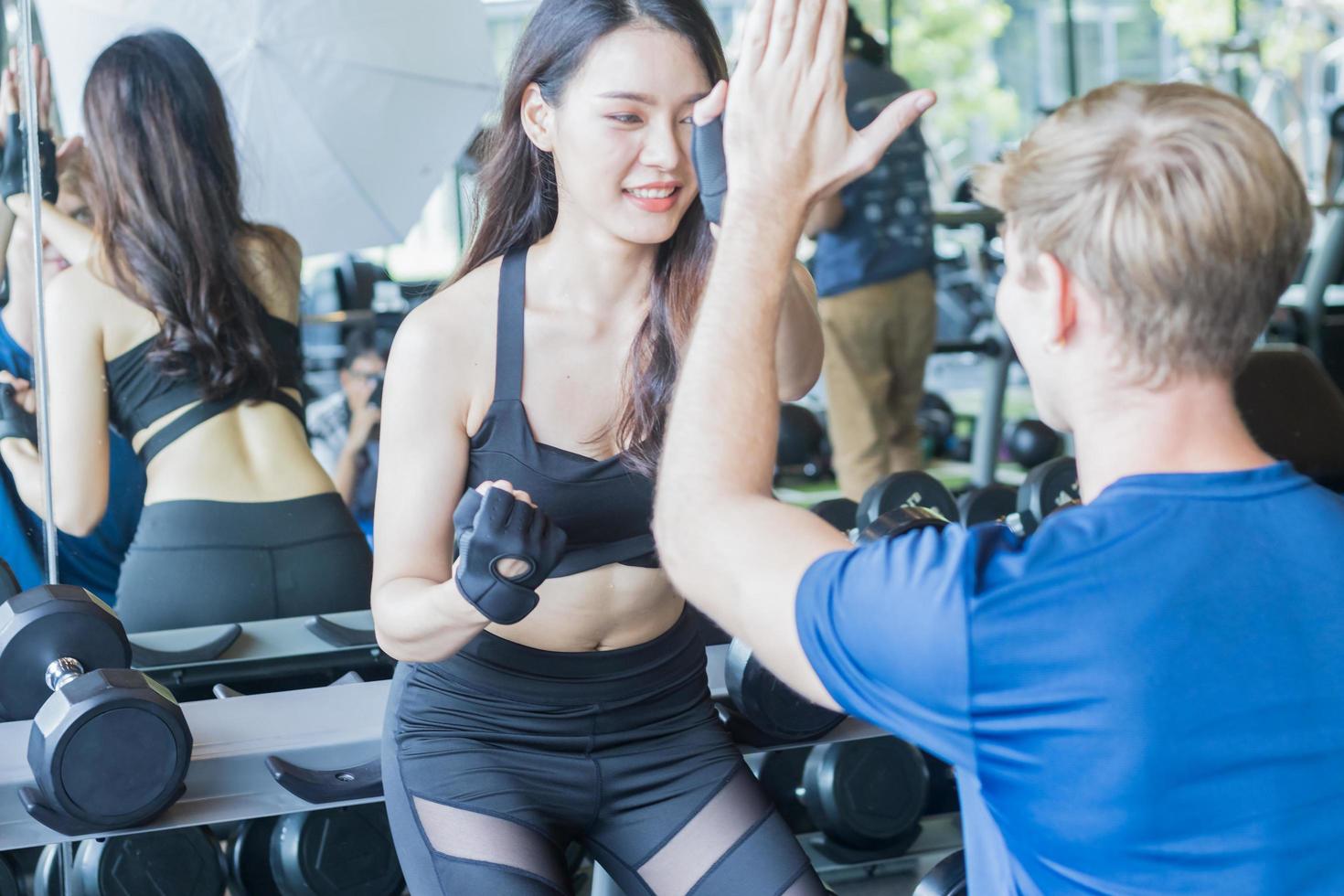 hermosa chica asiática haciendo ejercicio en el gimnasio con un joven entrenador para cuidar y entrenar. conceptos de ejercicio saludable foto