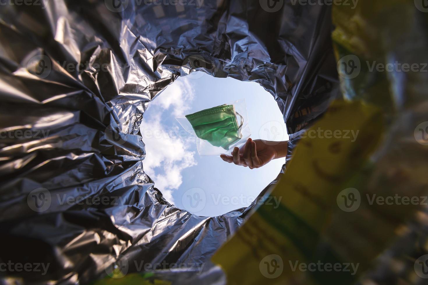 Face mask pack in zip lock before throw into the trash. With a worm view from the inside of the trash bin. photo