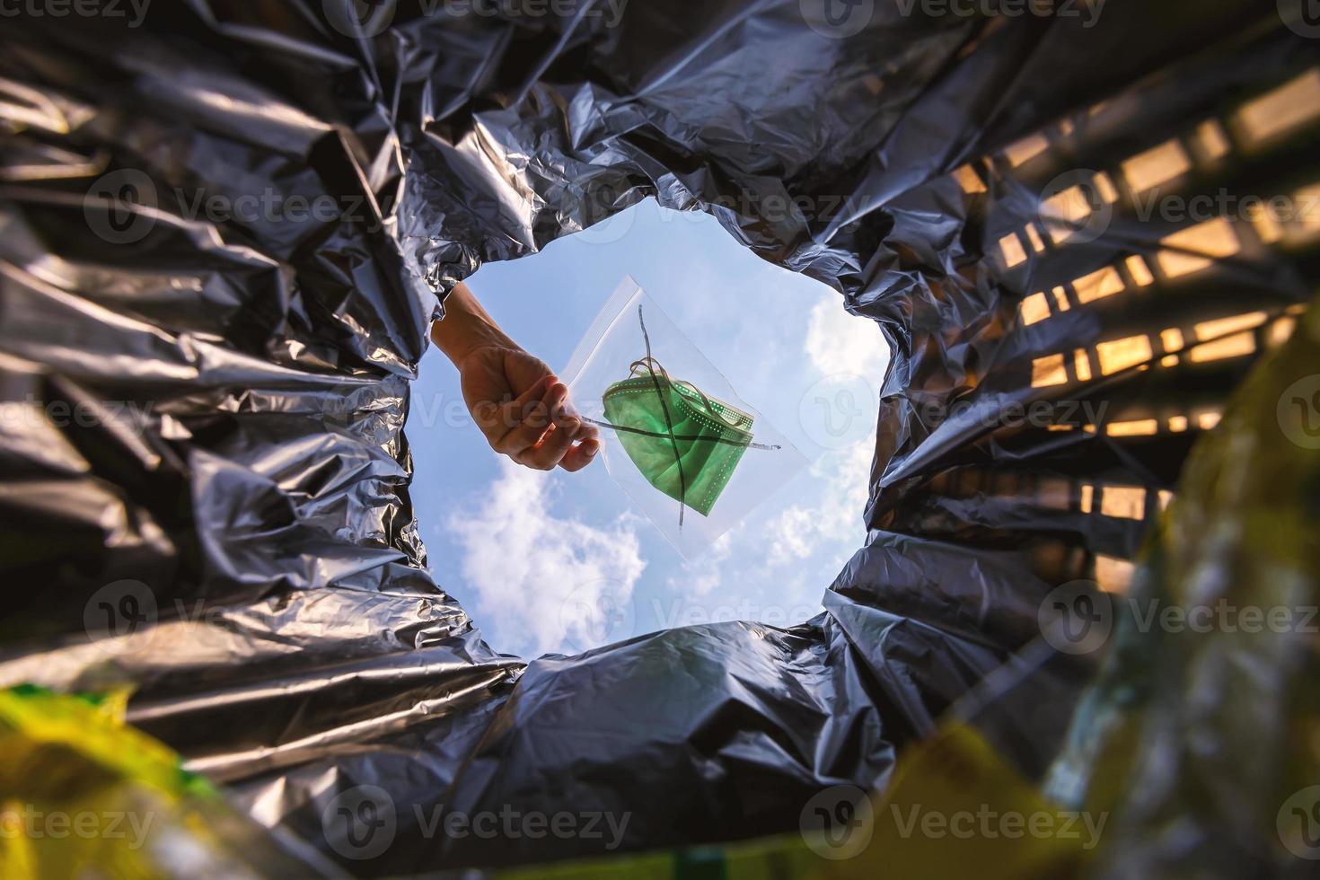 paquete de mascarilla con cierre de cremallera antes de tirarlo a la basura. con una vista de gusano desde el interior de la papelera. foto