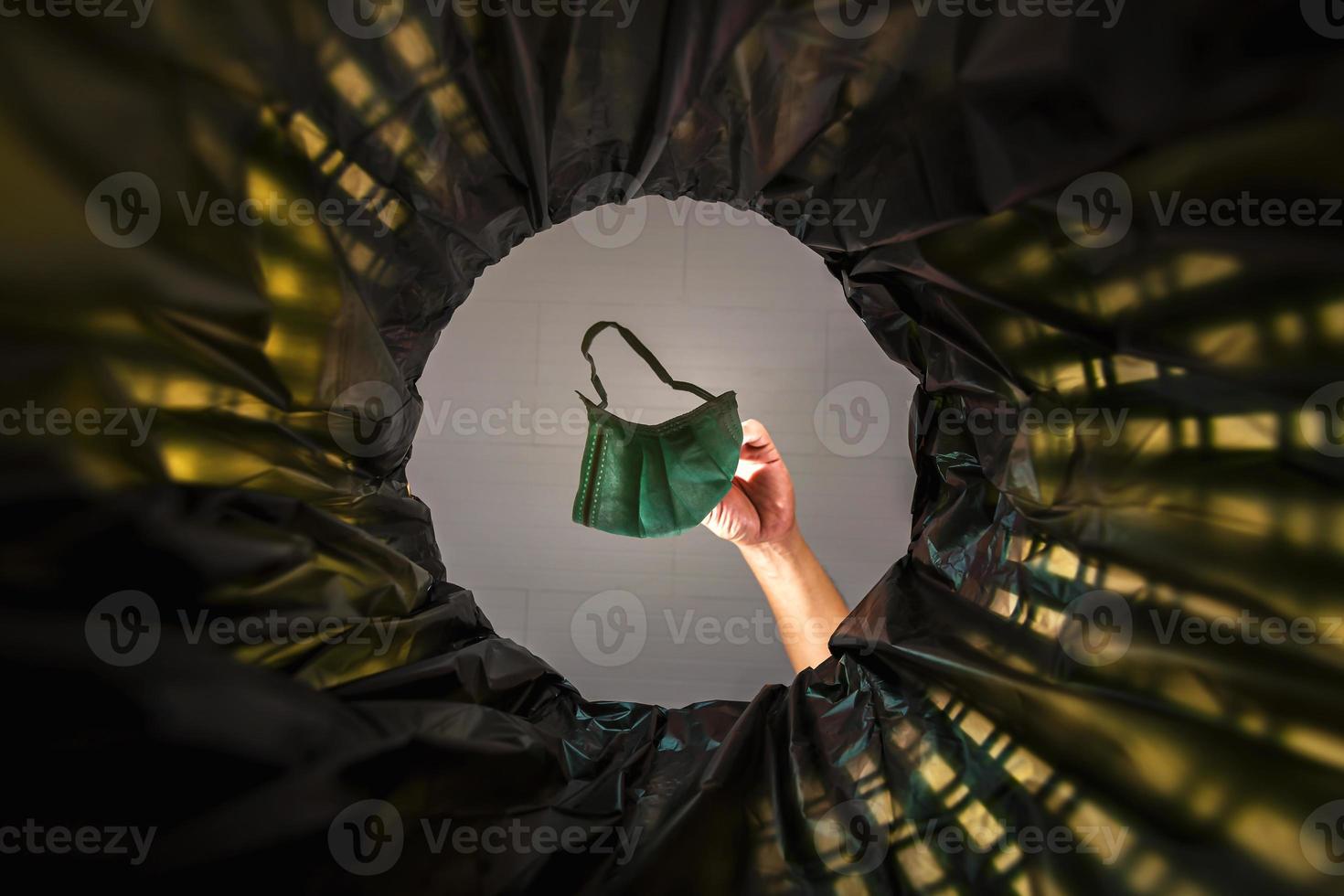 Throwing a face mask into the trash. With a worm view from the inside of the trash bin. photo