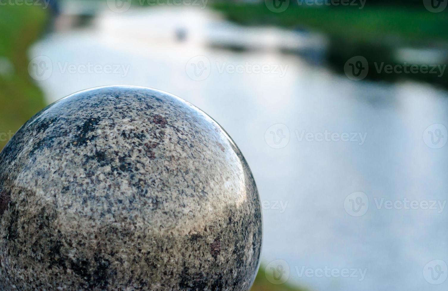 Gran bola de mármol decorativa con el fondo del río. foto
