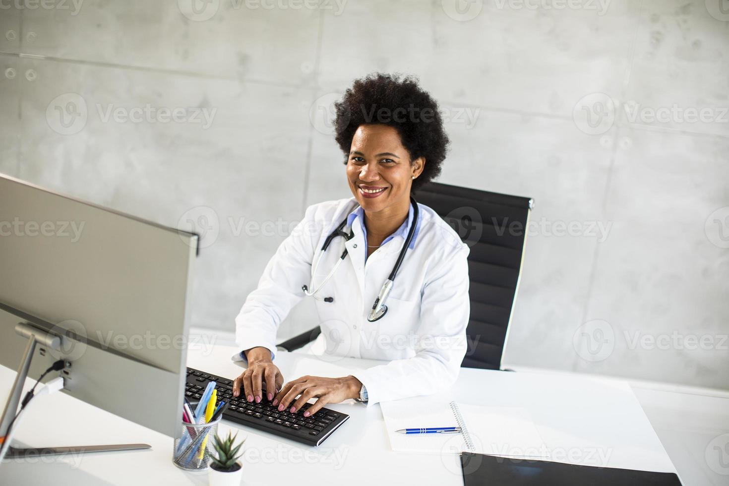 Doctor smiling while working on a computer photo