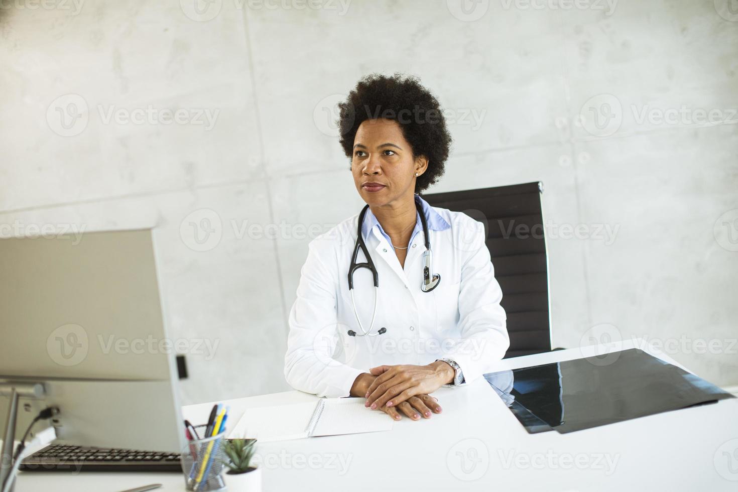 Doctor sitting at a desk looking away photo