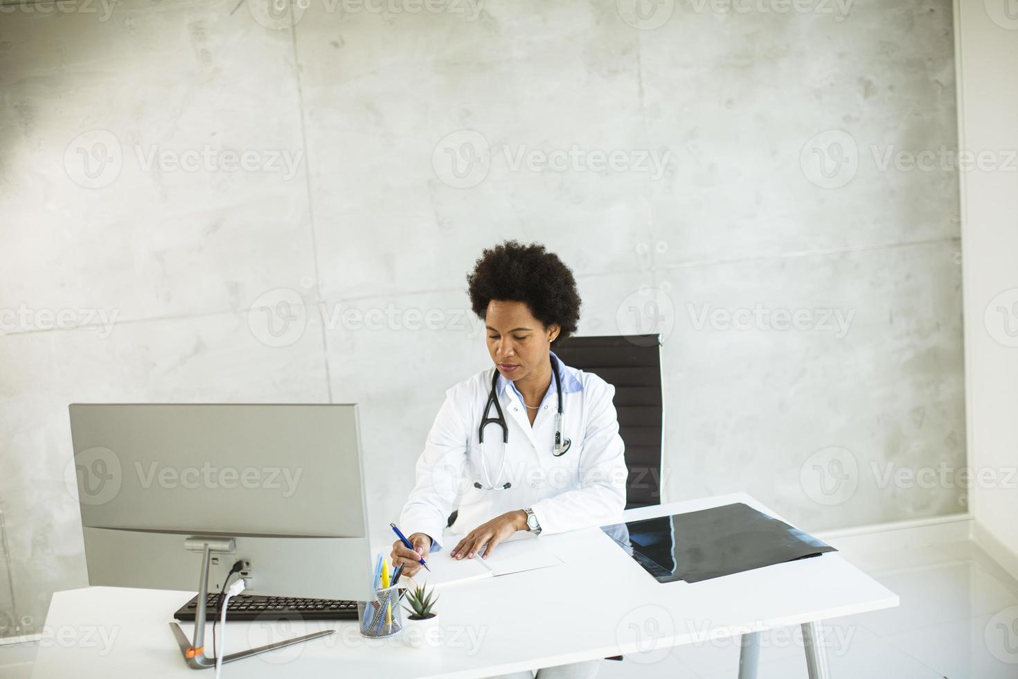 Doctor taking notes behind a desk photo