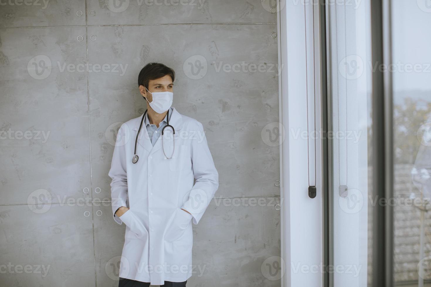 Doctor wearing a mask looking out a window photo