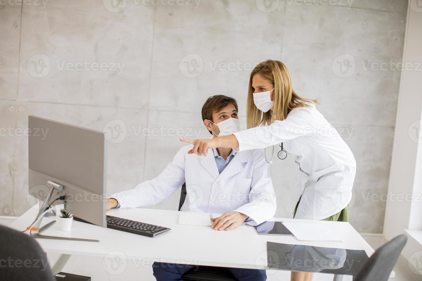 dos doctores enmascarados trabajando en una oficina foto