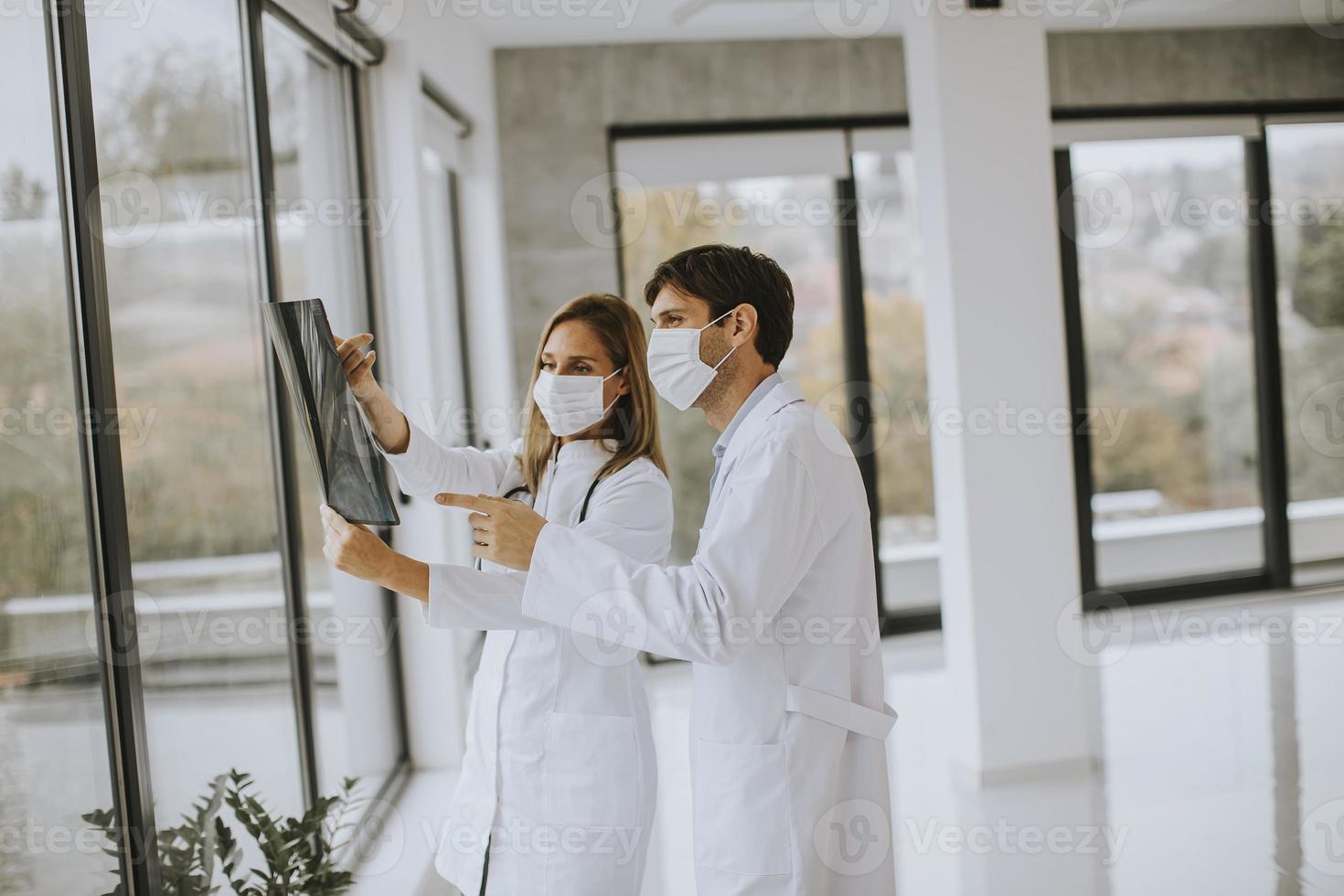 Two masked doctors looking at an x-ray photo