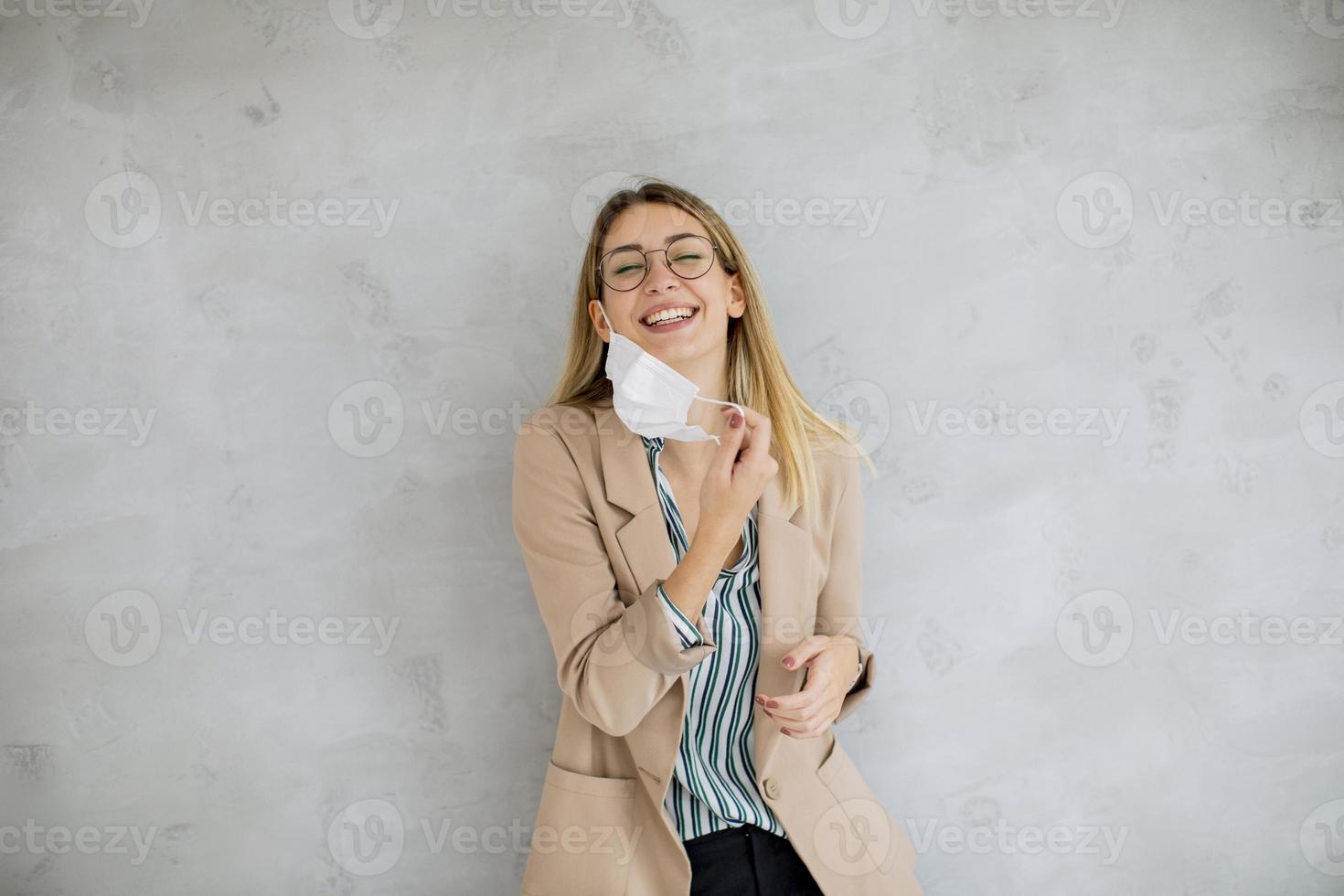 mujer contra una pared gris con una máscara foto