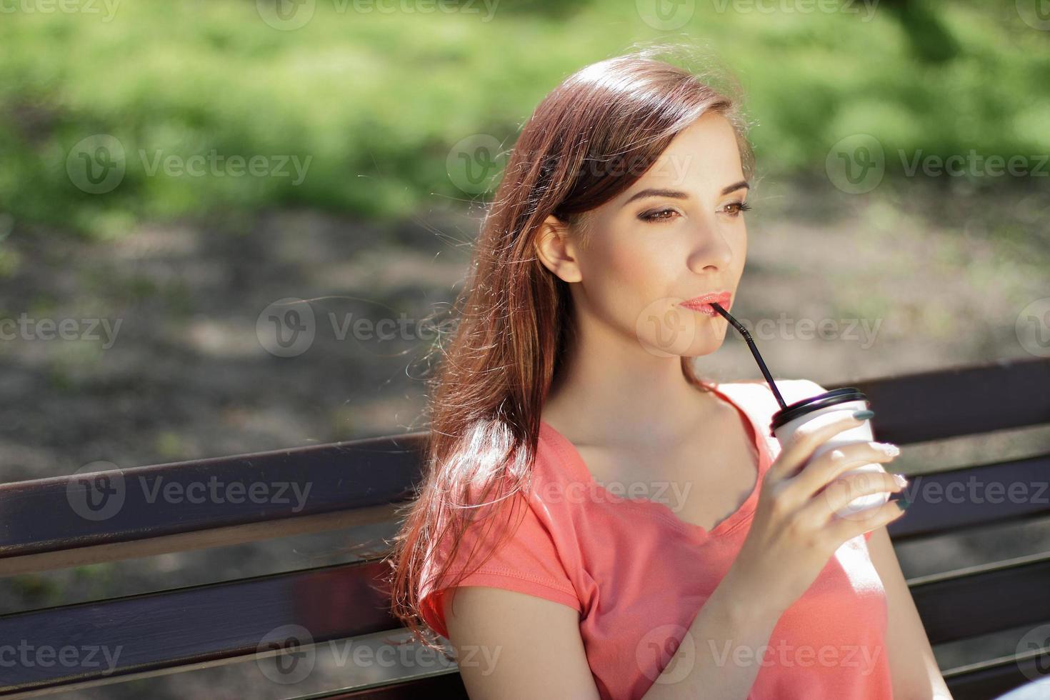 mujer tomando café en un banco del parque foto