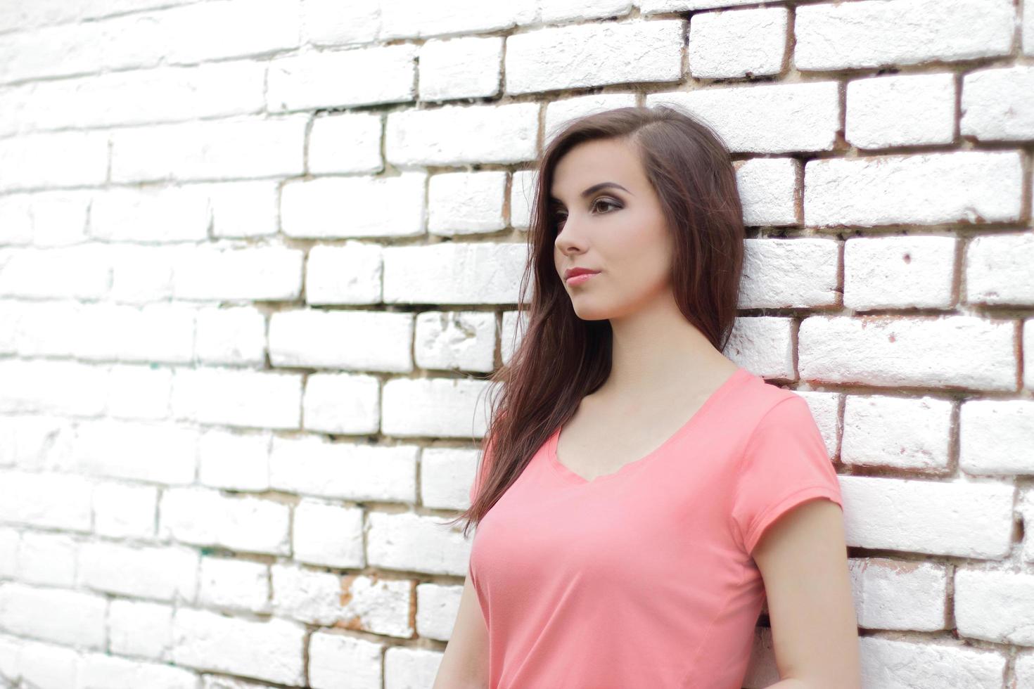 mujer recostada sobre una pared de ladrillo blanco foto