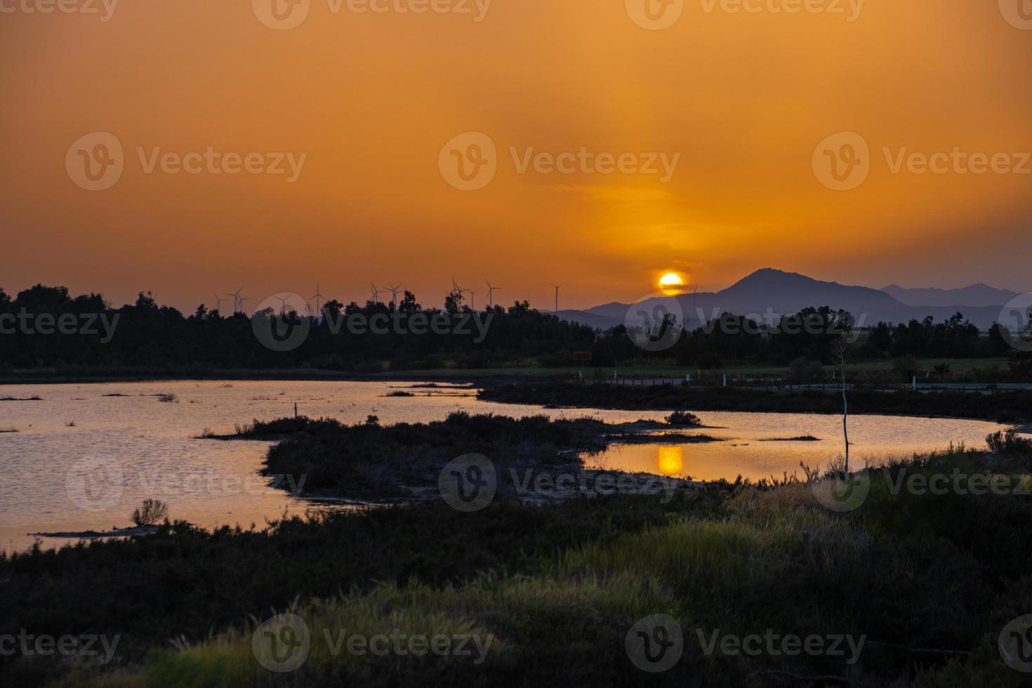 Sunset at the Larnaca salt lake witht he setting sun and wind turbines in the distance photo