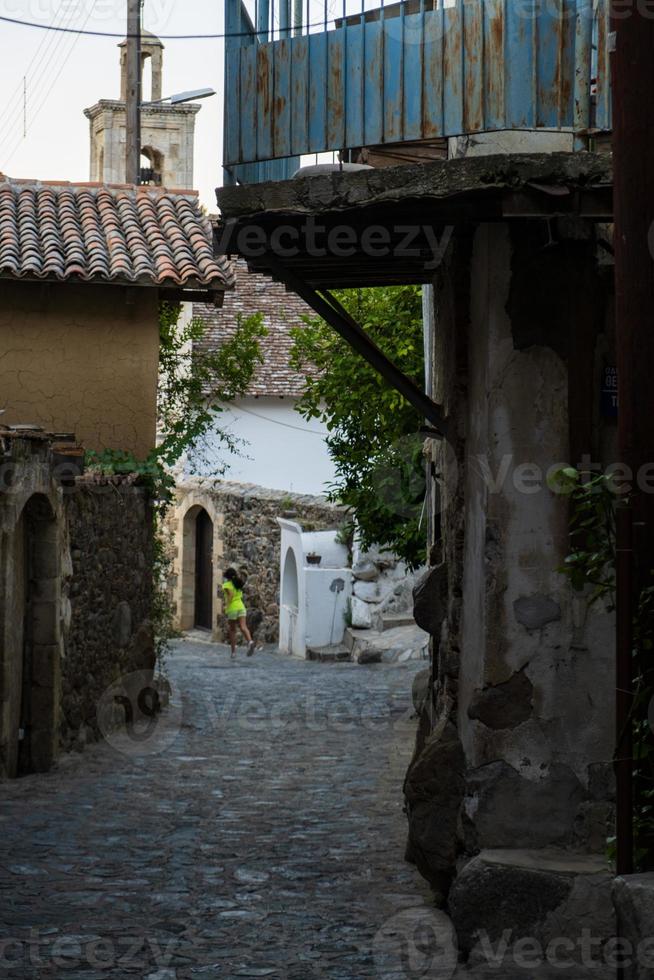 Pintorescas calles estrechas de Kakopetria antiguo en las montañas de Troodos en Chipre con una chica caminando en la distancia foto