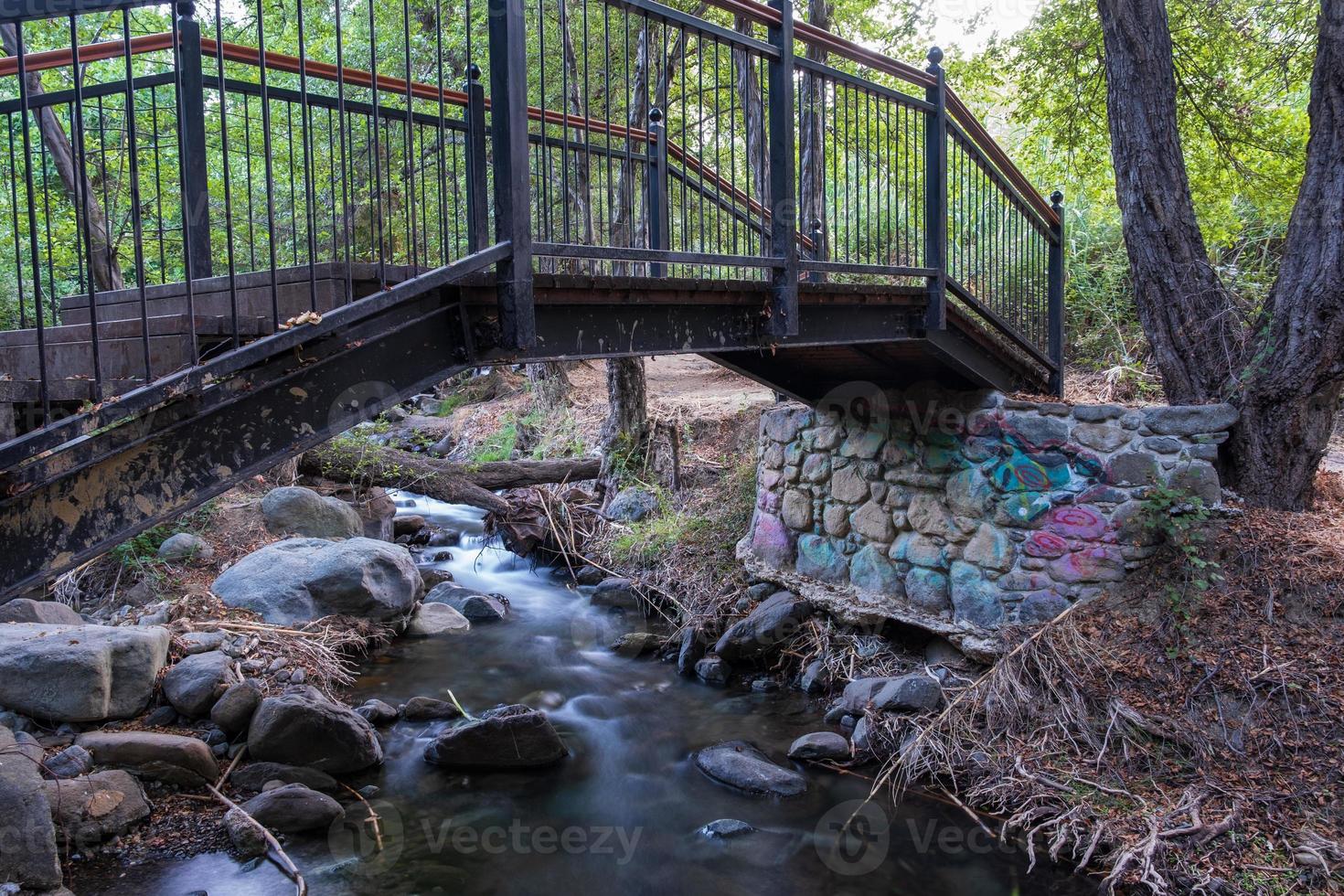 Bridge over smooth flowing water stream at the Vateri Footpah in Kakopetria in Cyprus photo