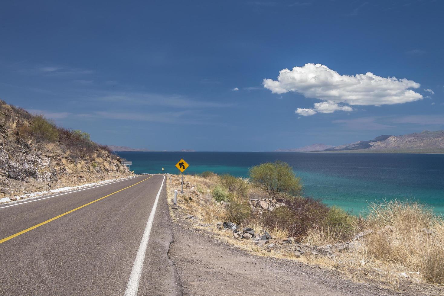 punta armenta en bahia concepcion baja california sur mexico con cielo azul y el mar de cortes en el fondo y la carretera de loreto a santa rosalia en las montañas en mulege foto