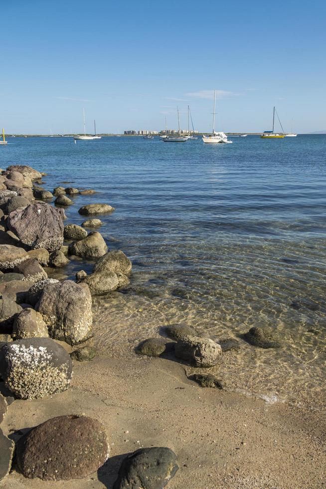 La Paz Baja California Sur Malecon by the sea of Cortes with rocks on the beach and calm seawater with El Mogote in the background photo