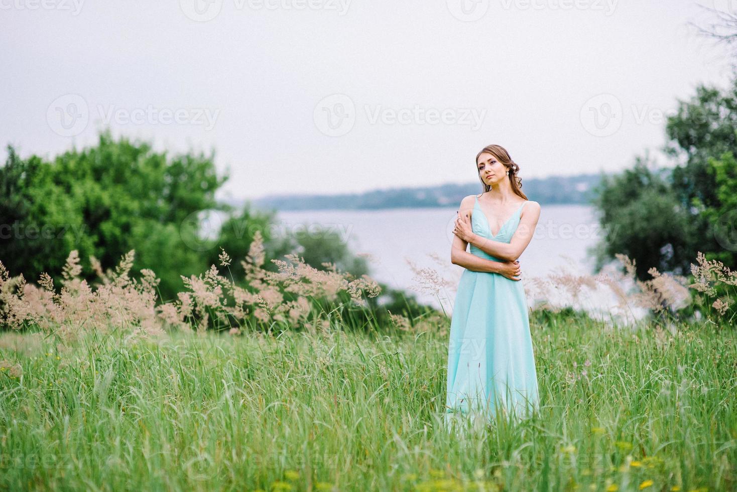 niña feliz en un vestido largo turquesa en un parque verde foto