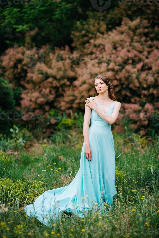 niña feliz en un vestido largo turquesa en un parque verde foto