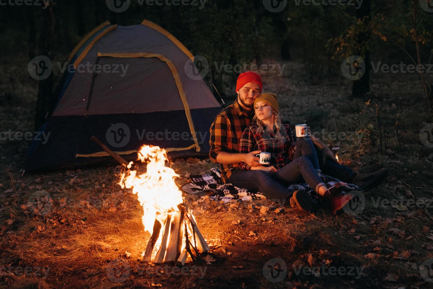 Pareja joven un chico y una chica con sombreros de punto brillantes se detuvieron en un camping foto