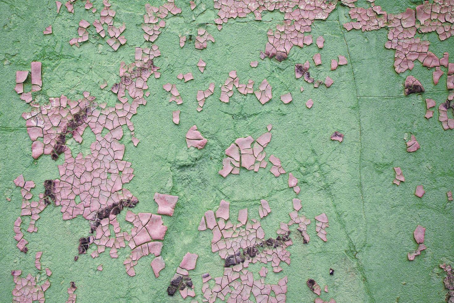 Damaged wall in abstract pink and green colors with peeling paint photo
