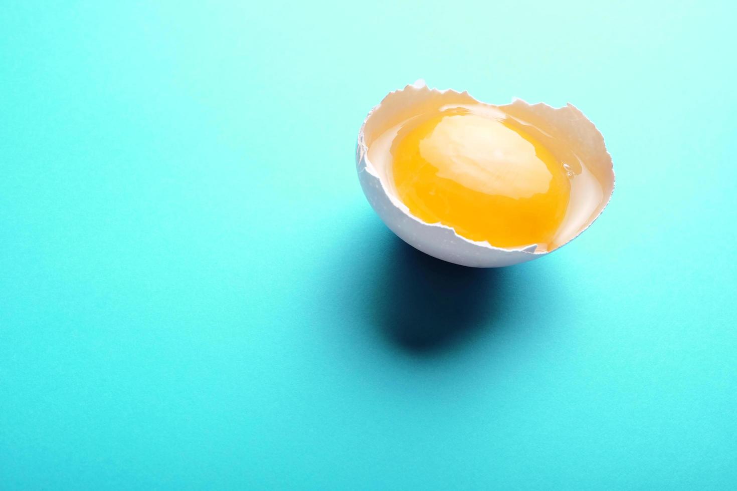 Broken egg on blue background photo