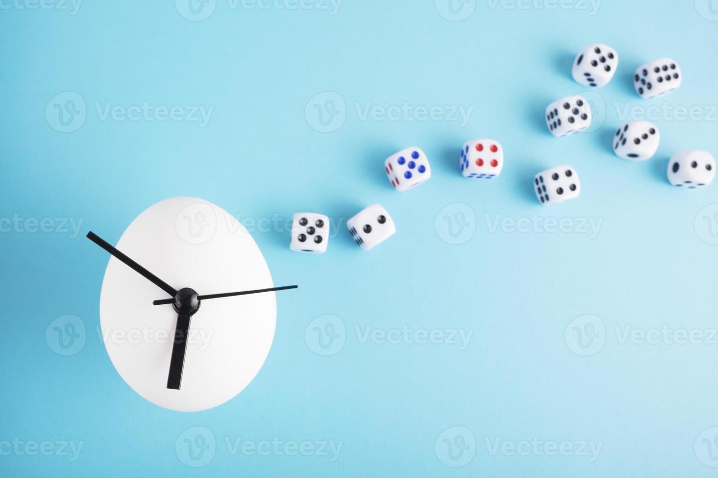 An egg clock with dice on blue background photo