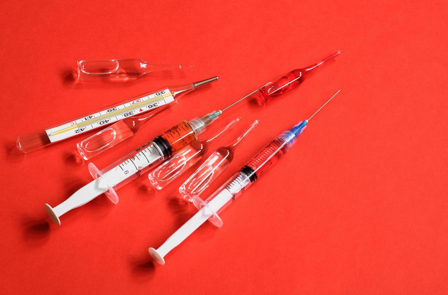 Syringes and ampules on blood red background photo