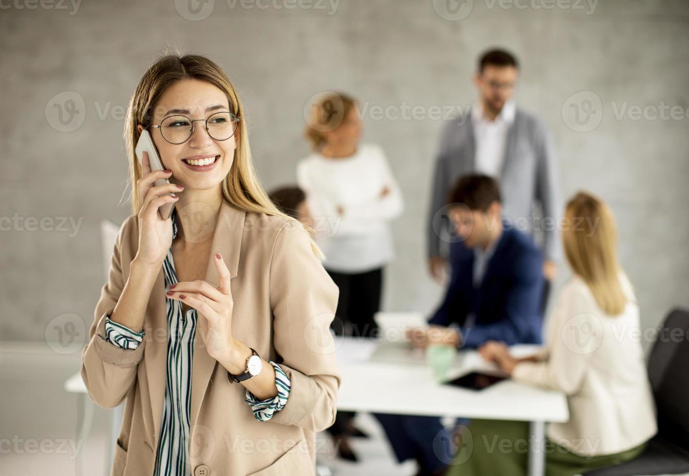 Woman on phone with meeting in the background photo