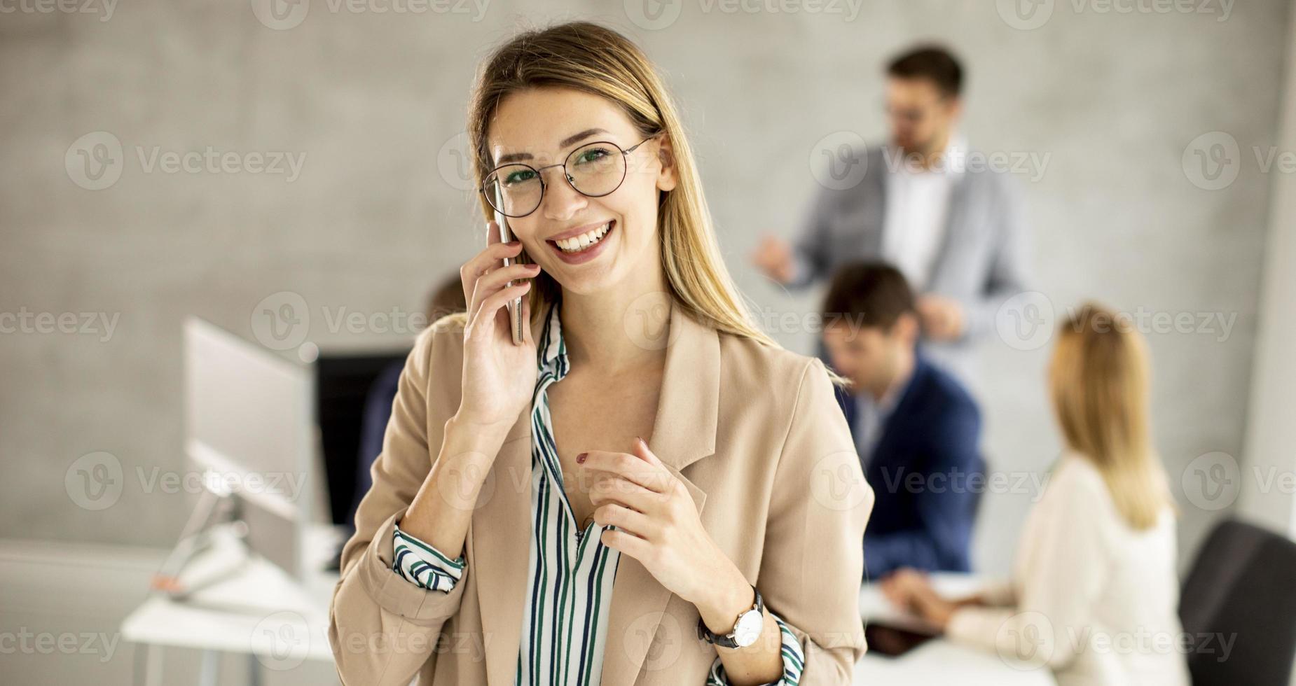 mujer hablando por teléfono con una reunión en el fondo foto