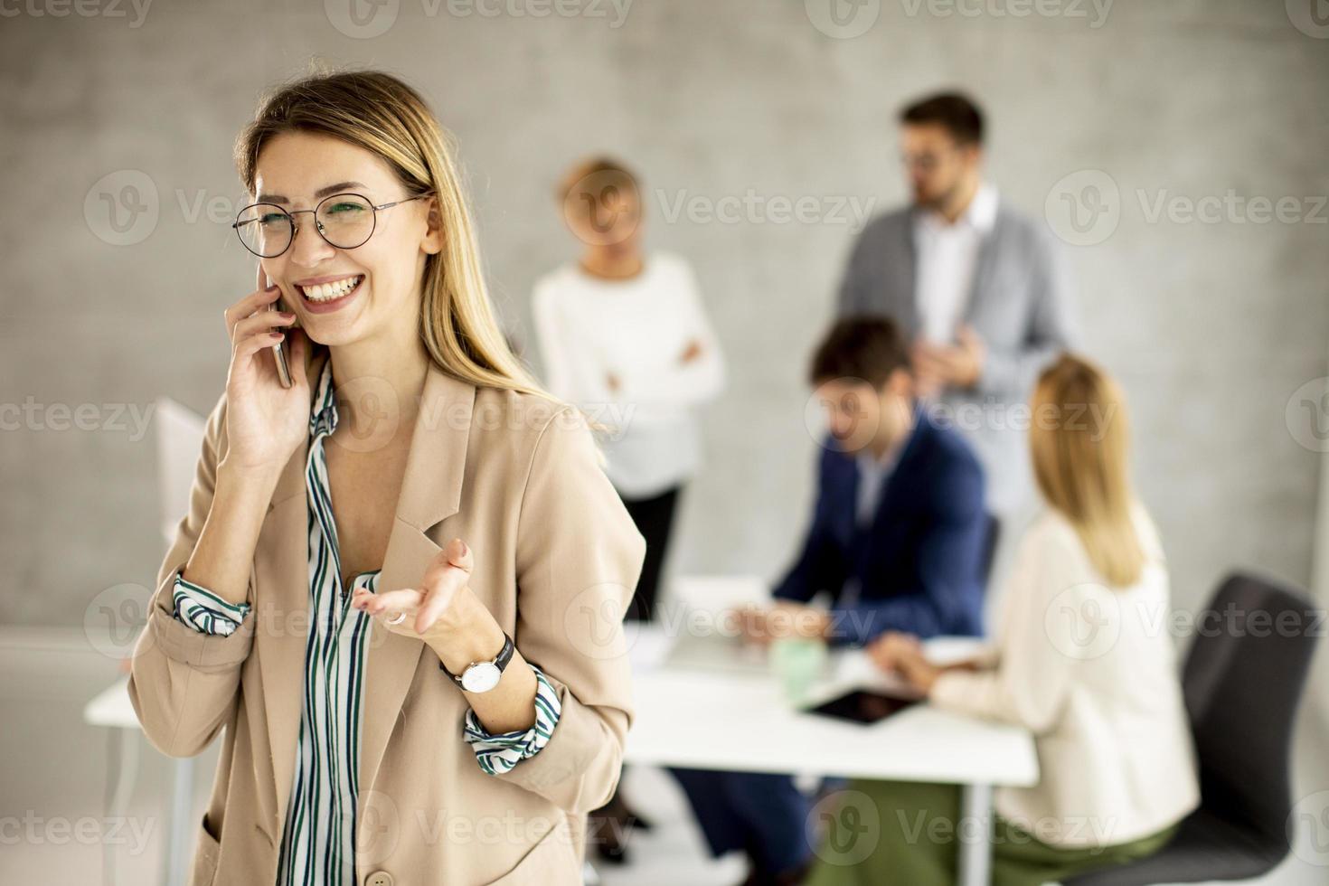 Woman talking on phone with meeting in the background photo