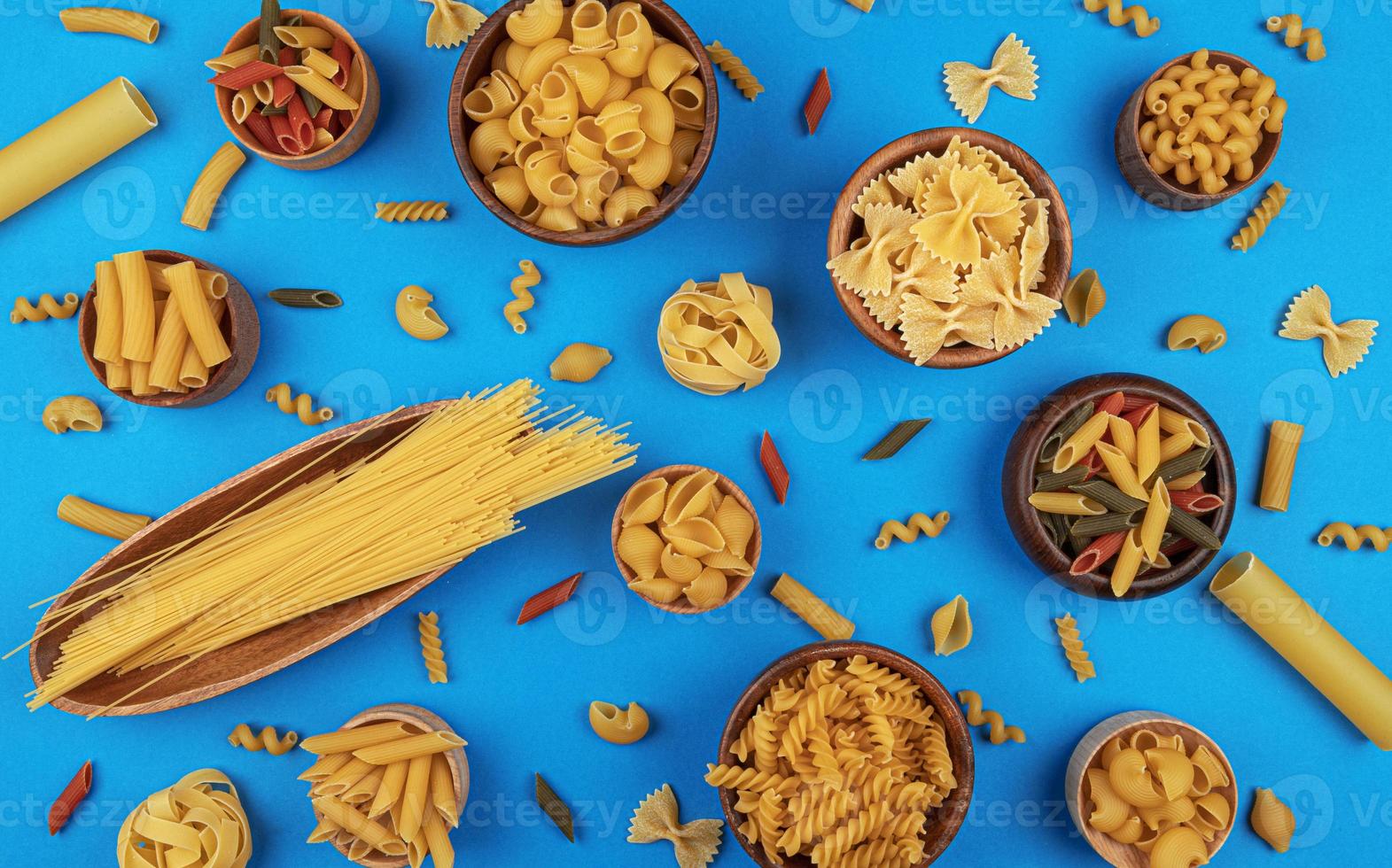 Different pasta types on blue background top view photo