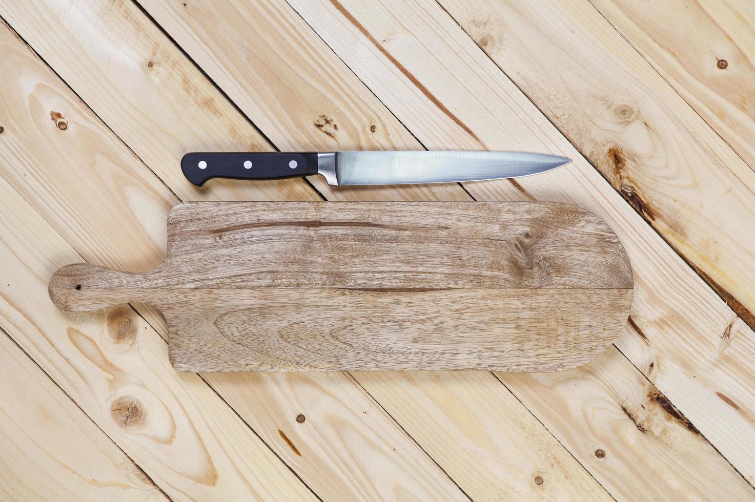Cutting board with knife on wooden table photo
