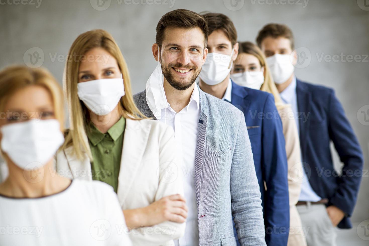 Business professionals wearing masks with man taking off mask photo