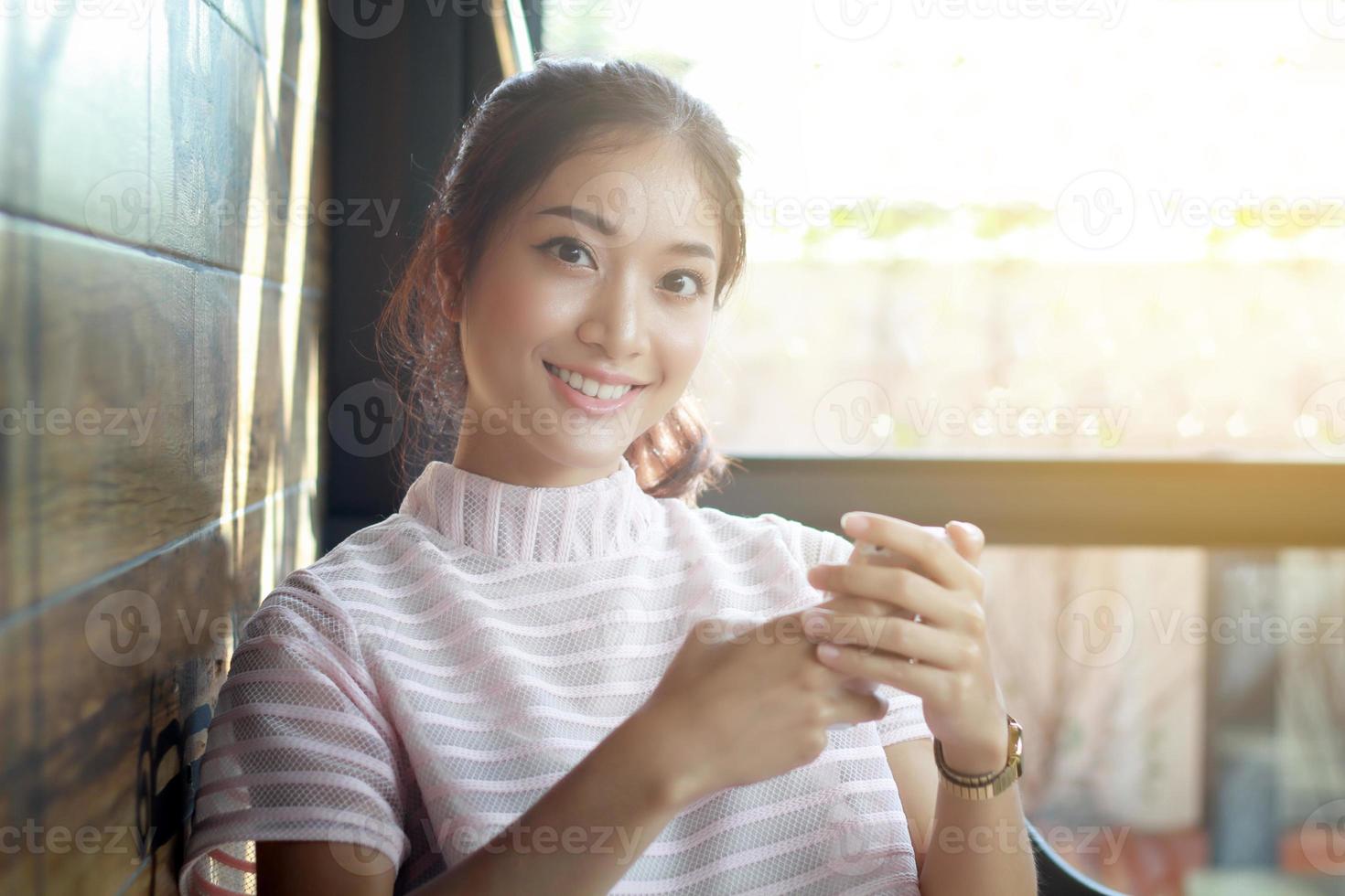 mujer asiática, utilizar, teléfono inteligente, en una mesa foto
