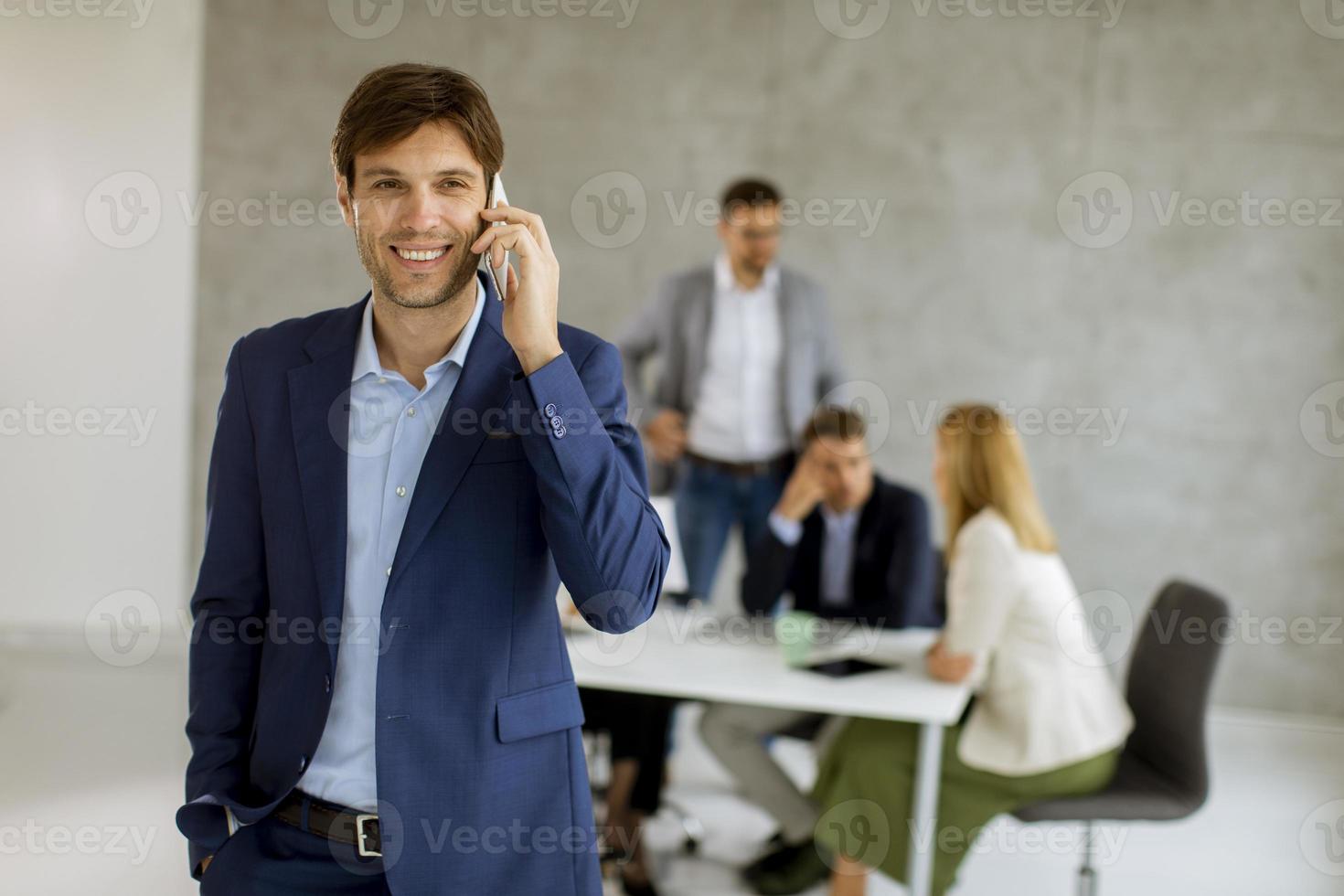 Man on phone with team in background photo