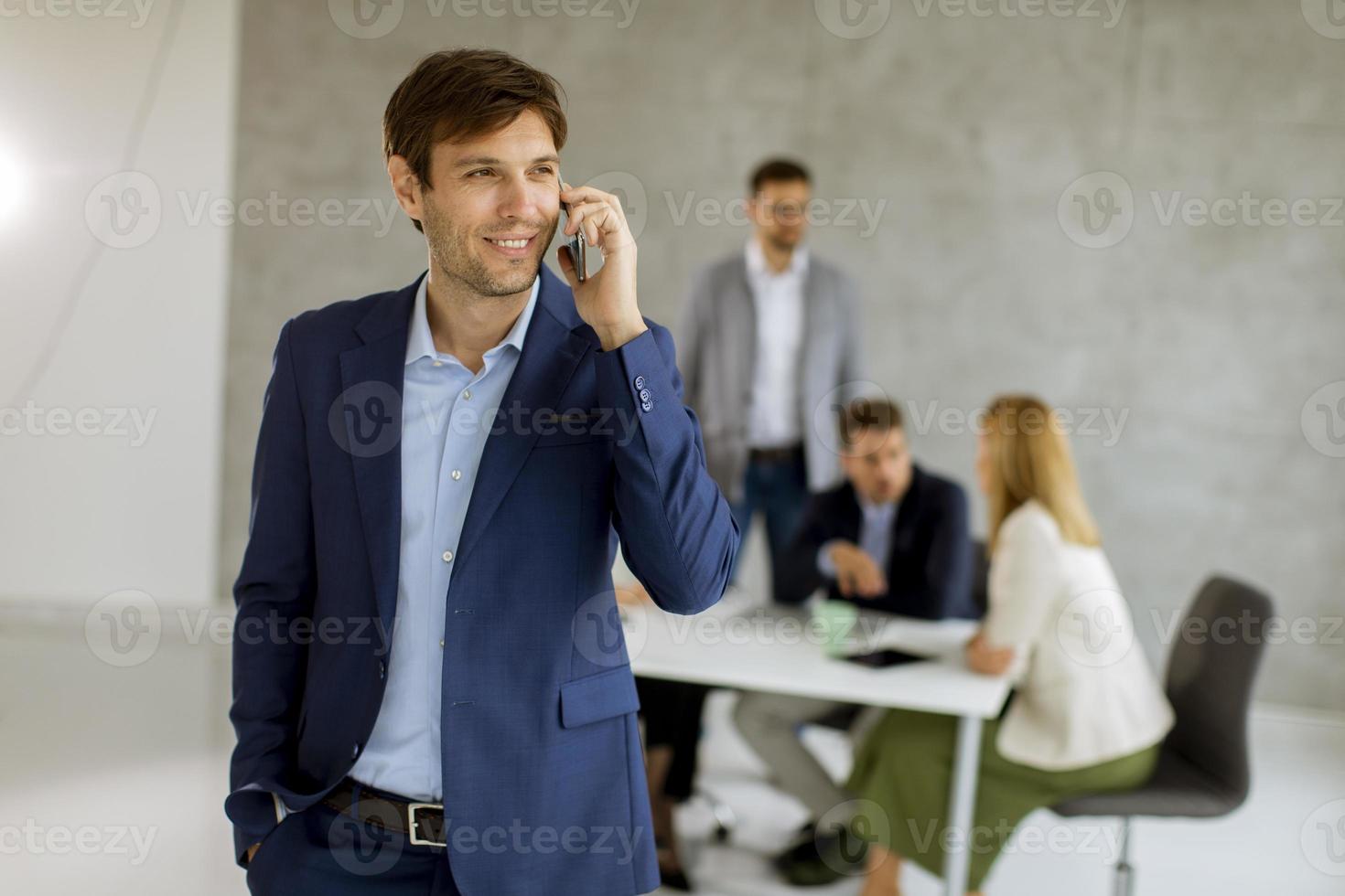 Man on phone while team is in a meeting photo