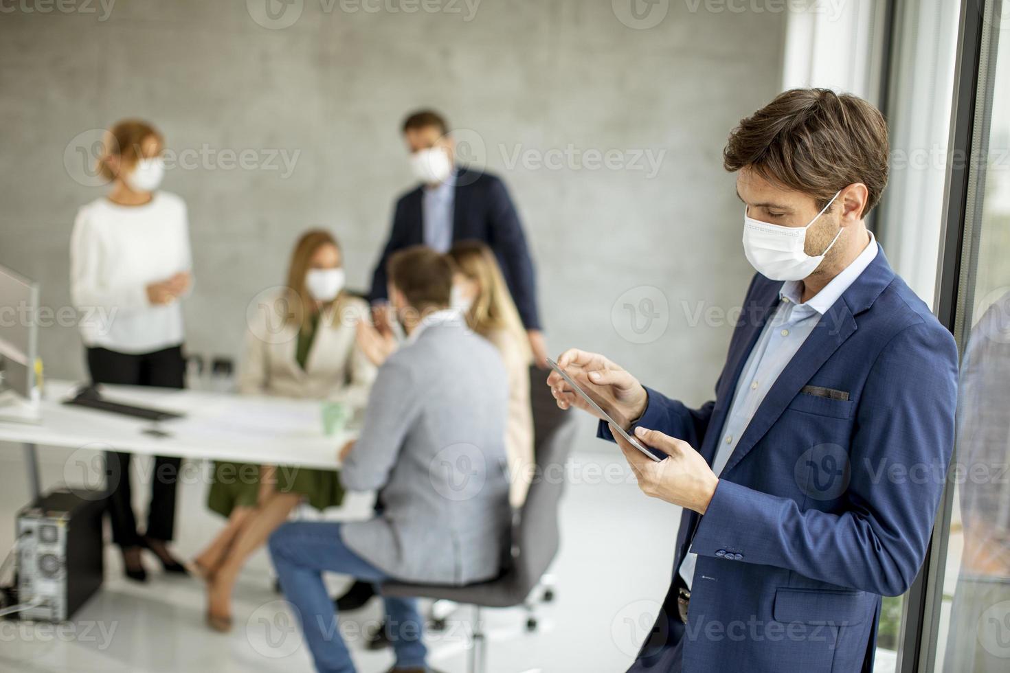 Man using a tablet while wearing a mask photo