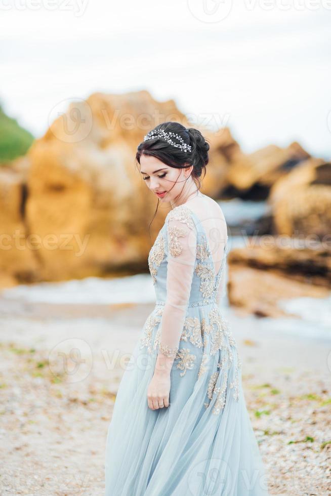 novia con un vestido azul claro caminando por el océano foto