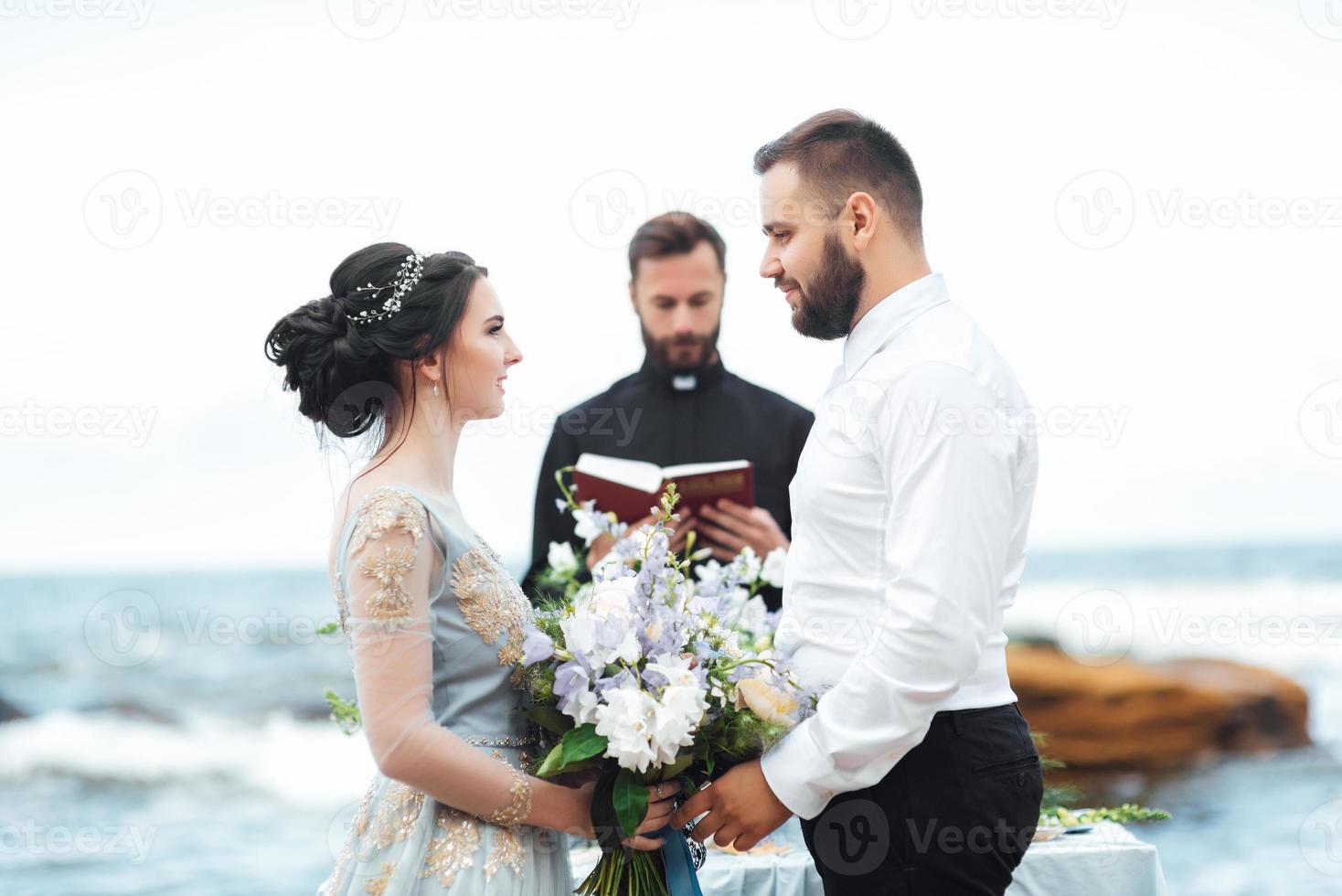 novios en el océano con un sacerdote foto