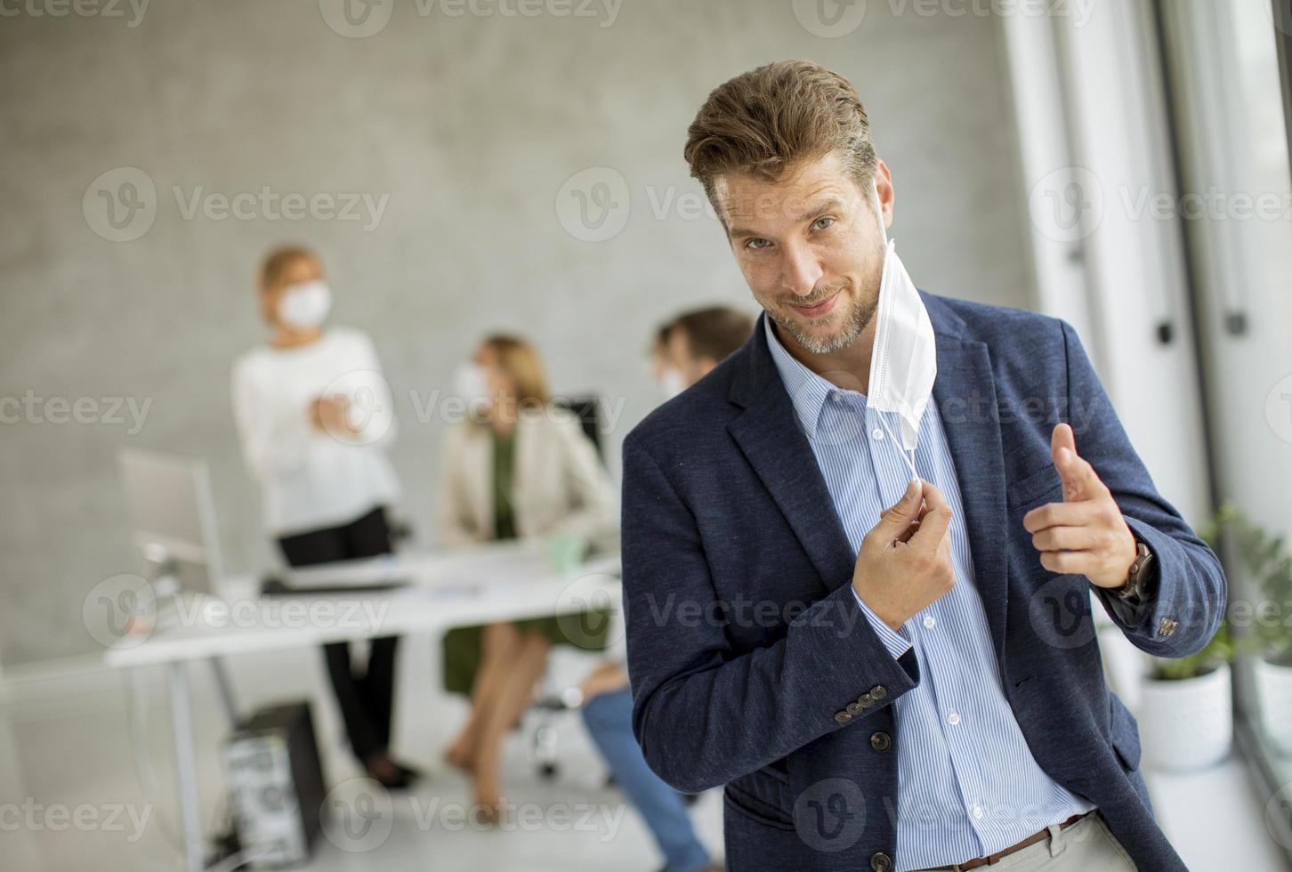 Man giving a thumbs up and taking off his mask photo
