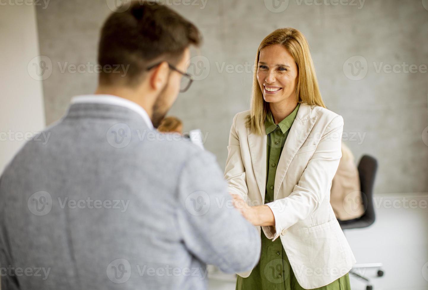 Two business people shaking hands in an office photo