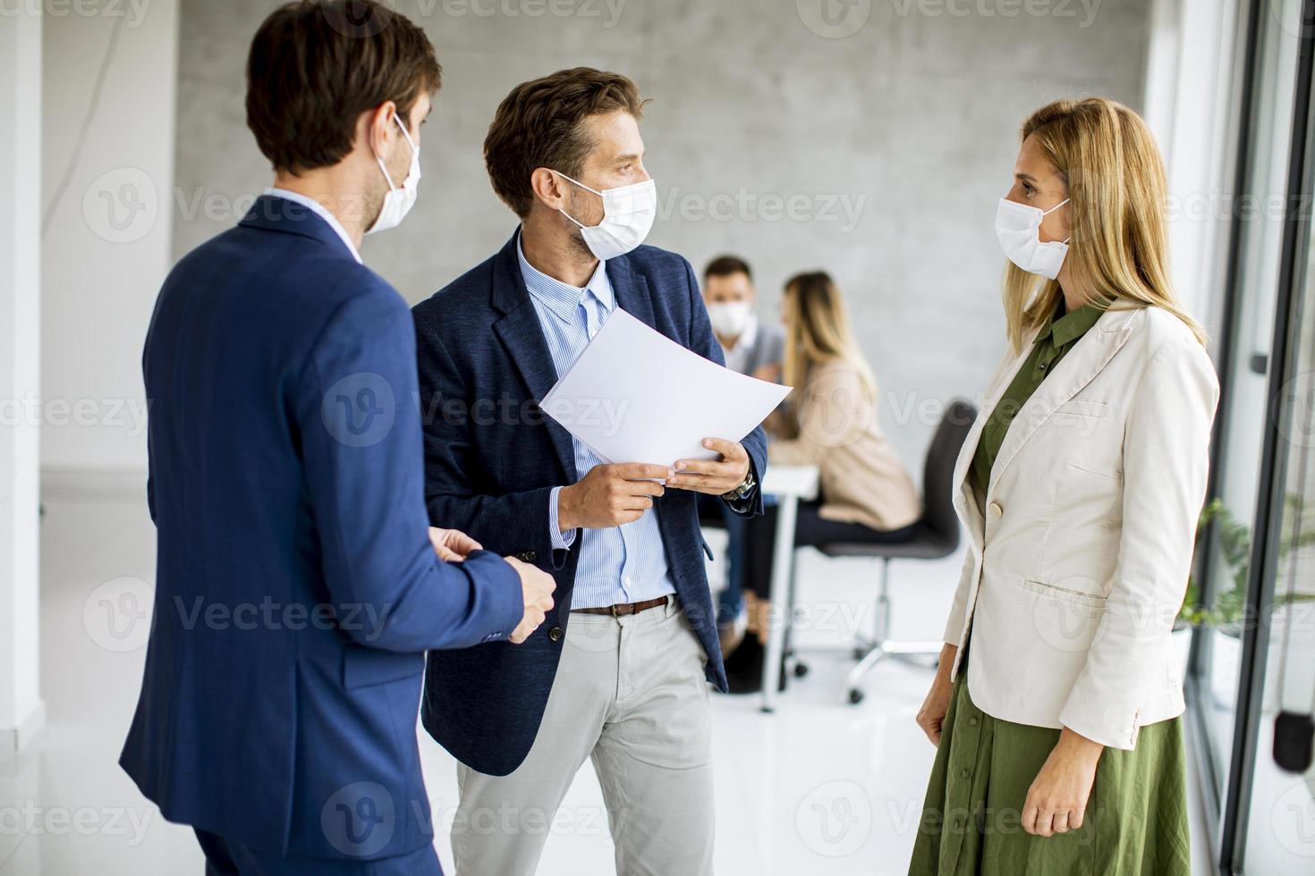 Three masked professionals discussing documents photo