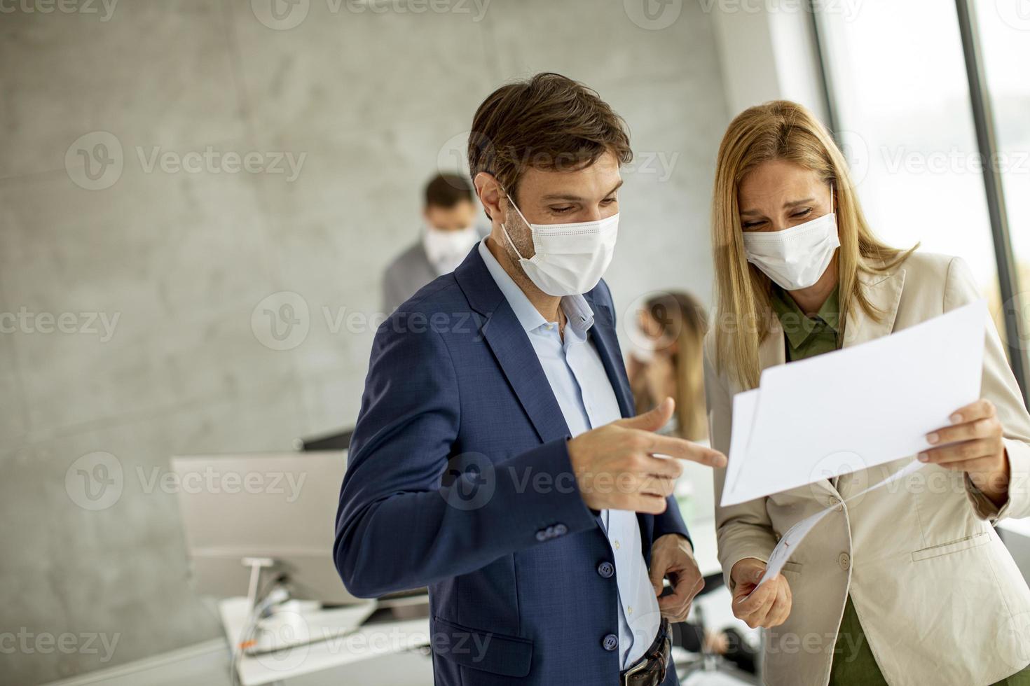 Close-up of masked professionals looking at a document photo