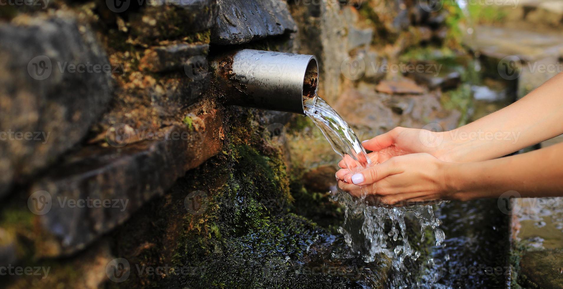 Banner of woman collecting pure water in hand from the source in the wall photo