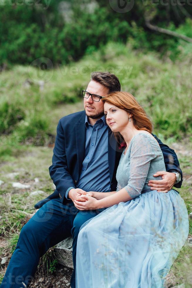 Young couple on a walk near the lake surrounded by the mountains photo